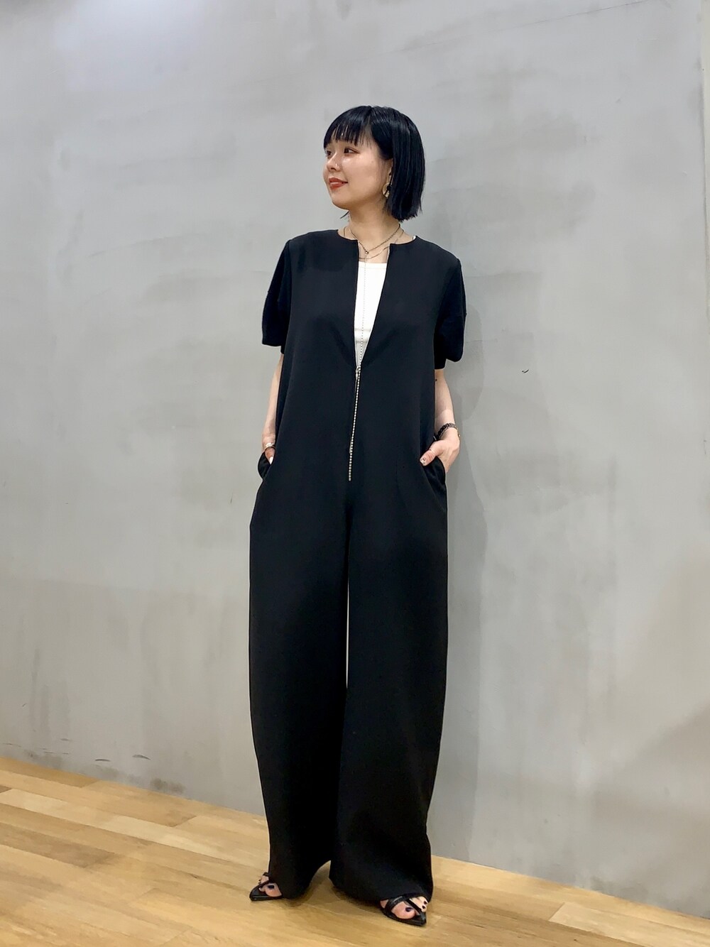 ブラック系のサロペット/オーバーオール、ブラック系のサンダル、ホワイト系のタンクトップを着用したレディースの夏コーディネートの1枚目の写真