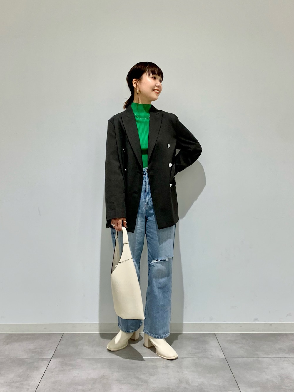 ブルー系のデニムパンツ、グレー系のテーラードジャケット、グリーン系のニット/セーターを着用したレディースの春コーディネートの1枚目の写真
