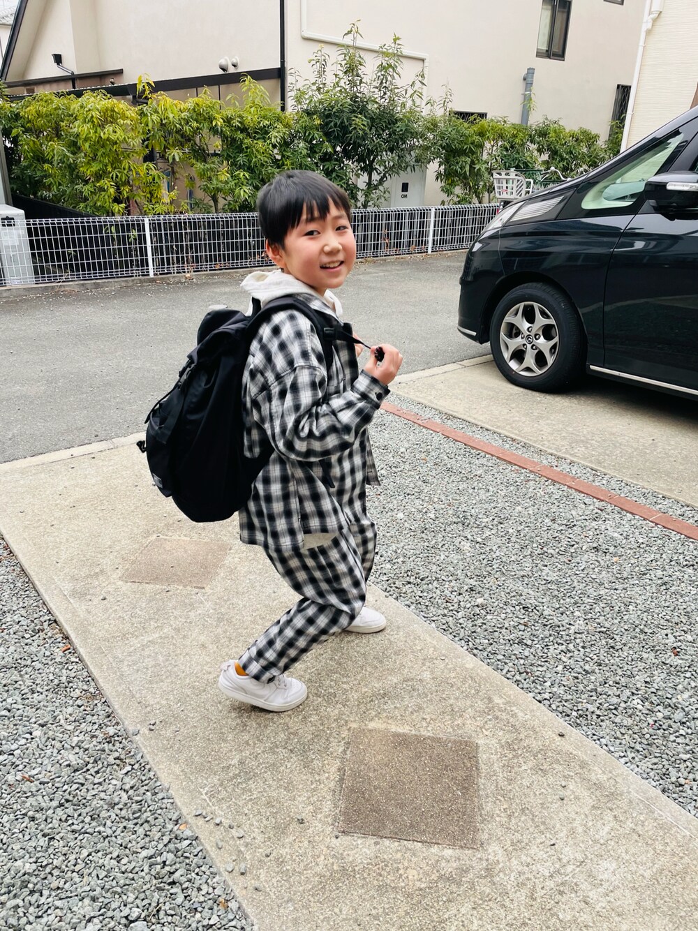 ブラック系のバックパック/リュック、グレー系のTシャツ/カットソー、ホワイト系のスニーカーを着用したキッズの冬コーディネートの1枚目の写真