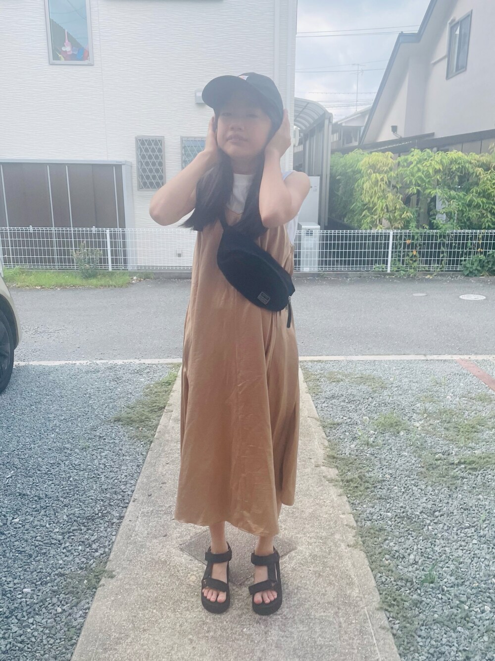 ベージュ系のジャンパースカート、ブラック系のサンダル、ブラック系のボディバッグ/ウエストポーチを着用したキッズの夏コーディネートの1枚目の写真