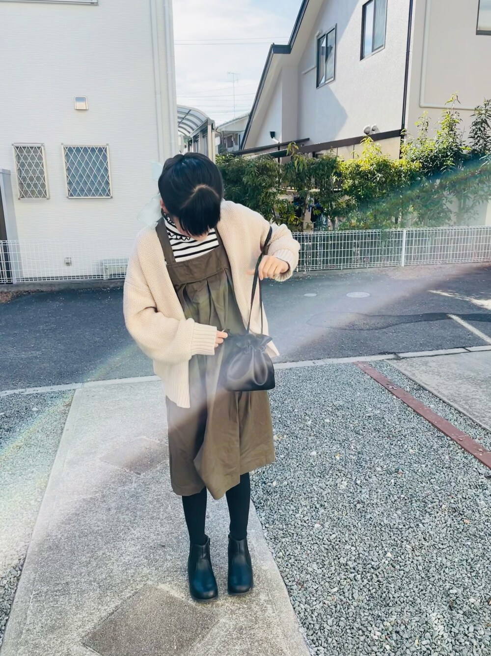 ホワイト系のカーディガン/ボレロ、グリーン系のジャンパースカート、ブラック系のブーツを着用したキッズの冬コーディネートの1枚目の写真