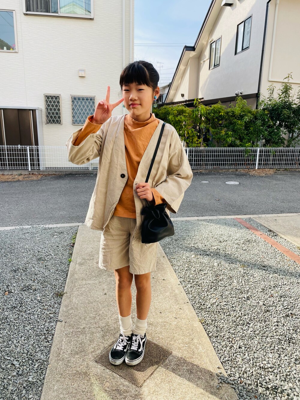 ベージュ系のジャケット/アウター、オレンジ系のTシャツ/カットソー、ブラック系のハンドバッグを着用したキッズの春コーディネートの1枚目の写真