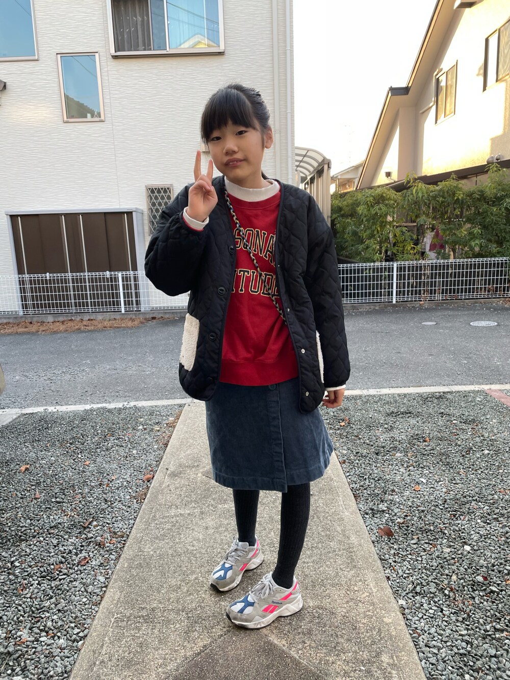 レッド系のスウェット、ブラック系のブルゾン、ブルー系のスカートを着用したキッズの冬コーディネートの1枚目の写真