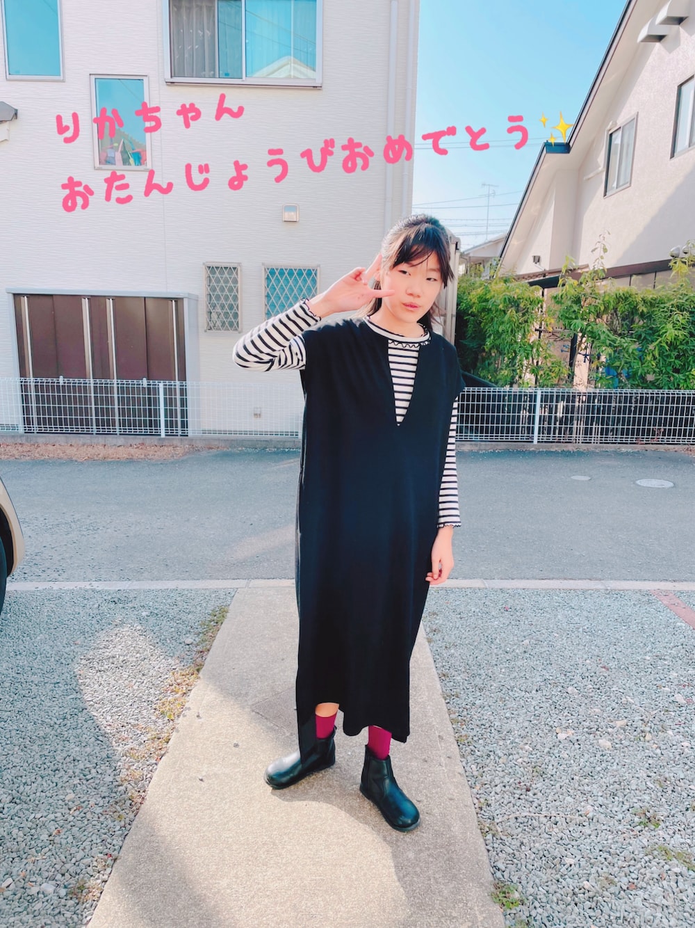 ブラック系のジャンパースカート、ブラック系のブーツを着用したキッズの春コーディネートの1枚目の写真