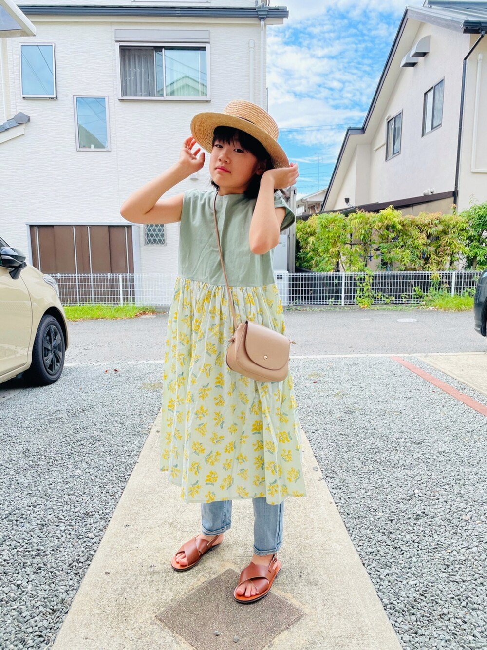 ベージュ系のショルダーバッグ、ブラウン系のサンダル、ブルー系のデニムパンツを着用したキッズの夏コーディネートの1枚目の写真