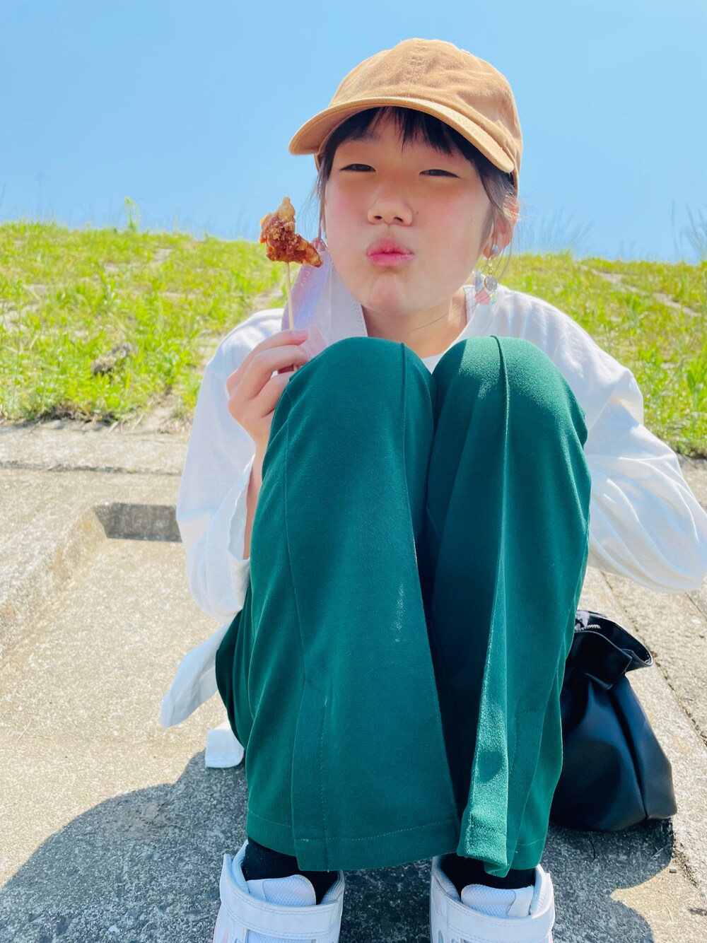 グリーン系のその他パンツ、ホワイト系のTシャツ/カットソー、ブラック系のハンドバッグを着用したキッズの春コーディネートの1枚目の写真