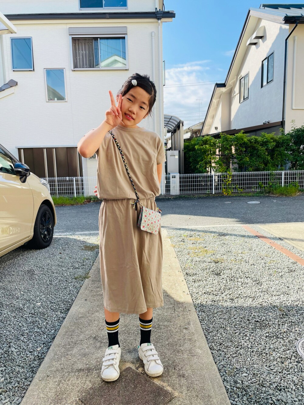 ベージュ系のワンピース、ホワイト系のスニーカー、ブラック系のTシャツ/カットソーを着用したキッズの秋コーディネートの1枚目の写真