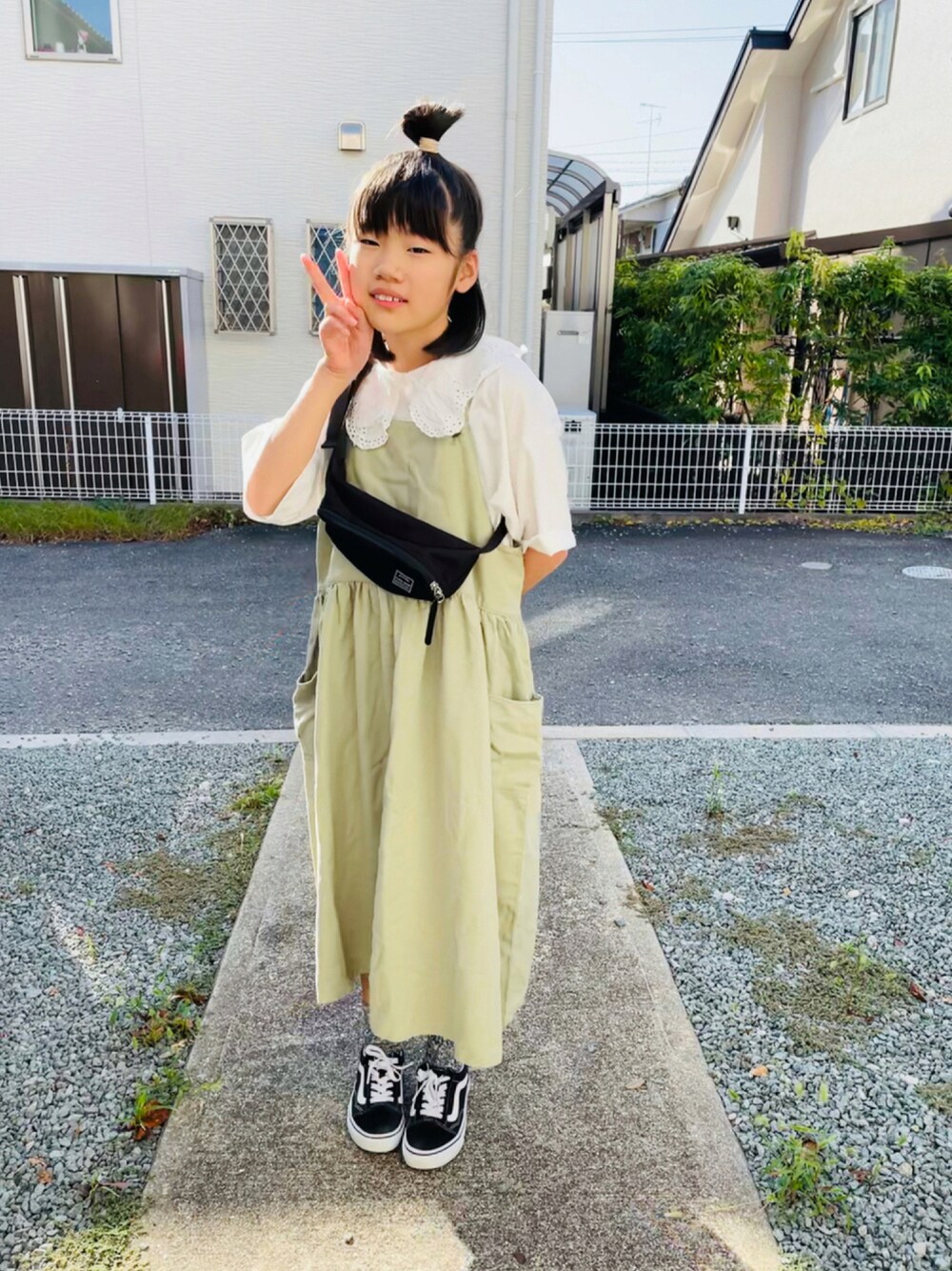グリーン系のワンピース、ブラック系のスニーカー、ホワイト系のTシャツ/カットソーを着用したキッズの秋コーディネートの1枚目の写真