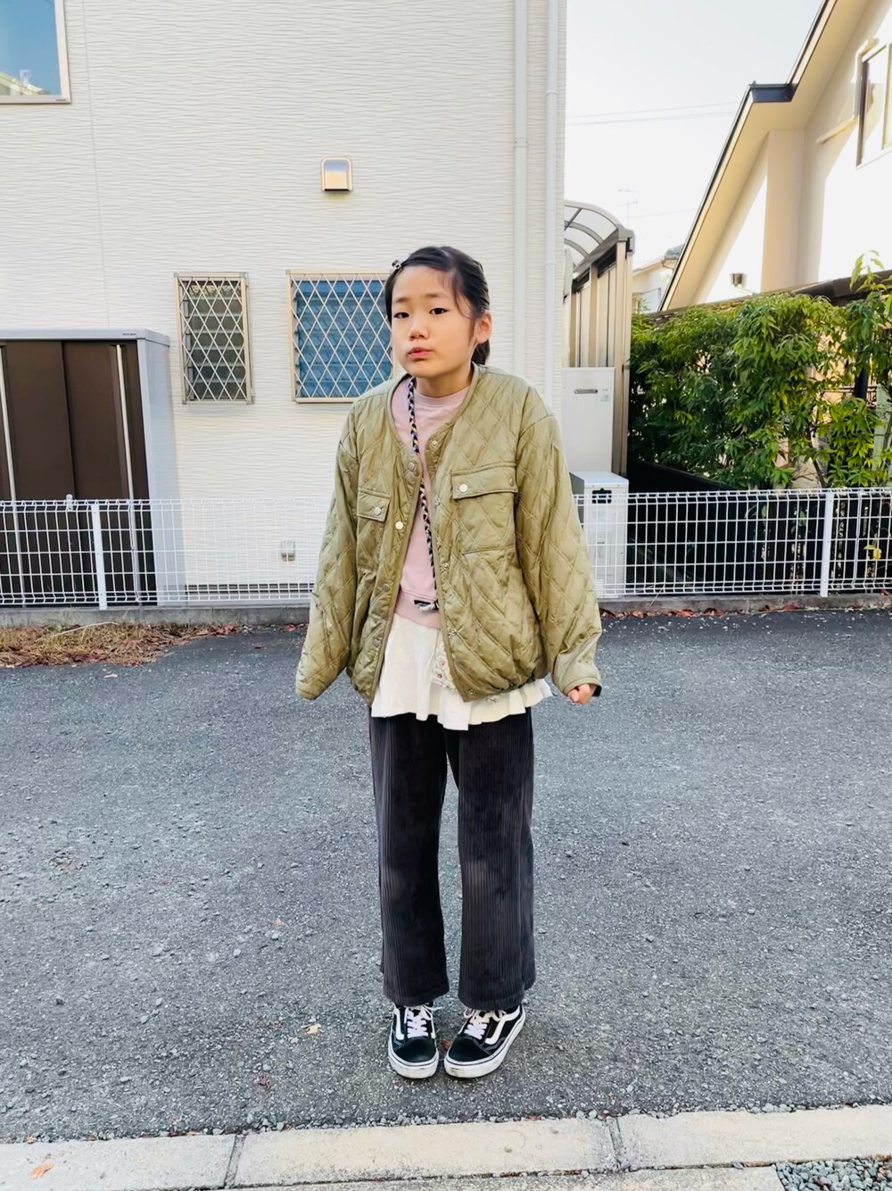グリーン系のブルゾン、グレー系のその他パンツ、ホワイト系のタンクトップを着用したキッズの秋コーディネートの1枚目の写真