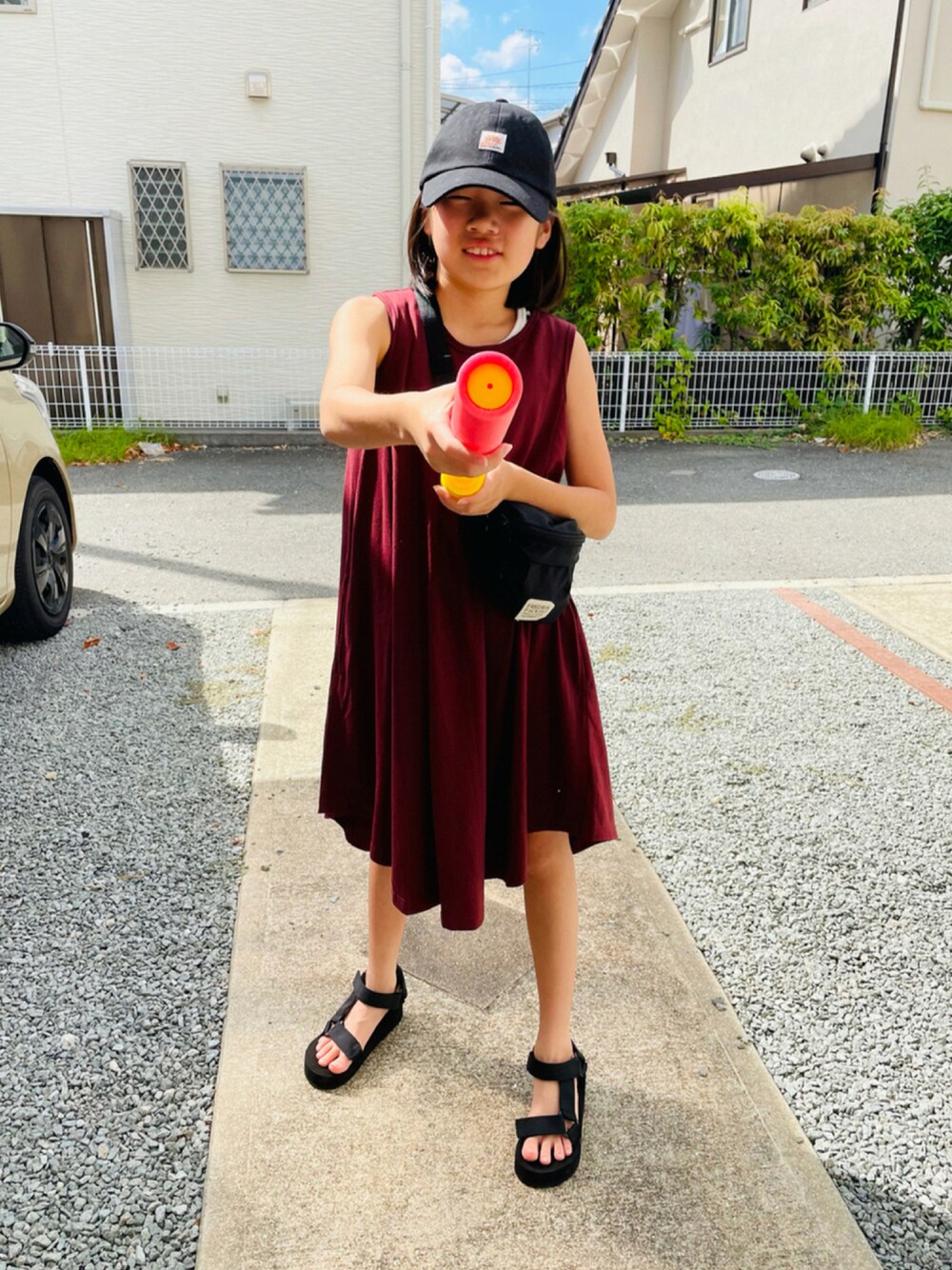 ブラウン系のワンピース、ブラック系のサンダル、ブラック系のボディバッグ/ウエストポーチを着用したキッズの夏コーディネートの1枚目の写真
