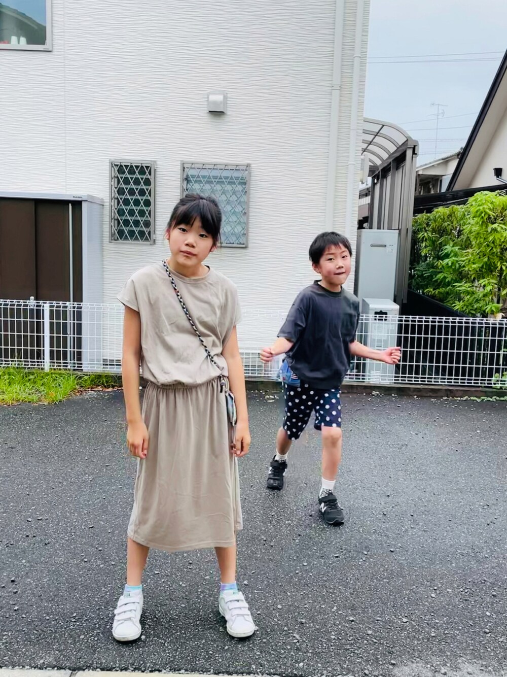 ベージュ系のワンピース、グリーン系のスニーカー、グレー系のTシャツ/カットソーを着用したキッズの夏コーディネートの1枚目の写真