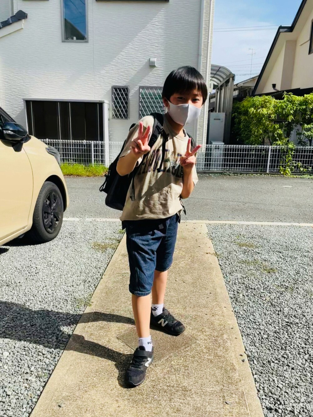 ベージュ系のTシャツ/カットソー、ブルー系のデニムパンツ、ブラック系のスニーカーを着用したキッズの秋コーディネートの1枚目の写真