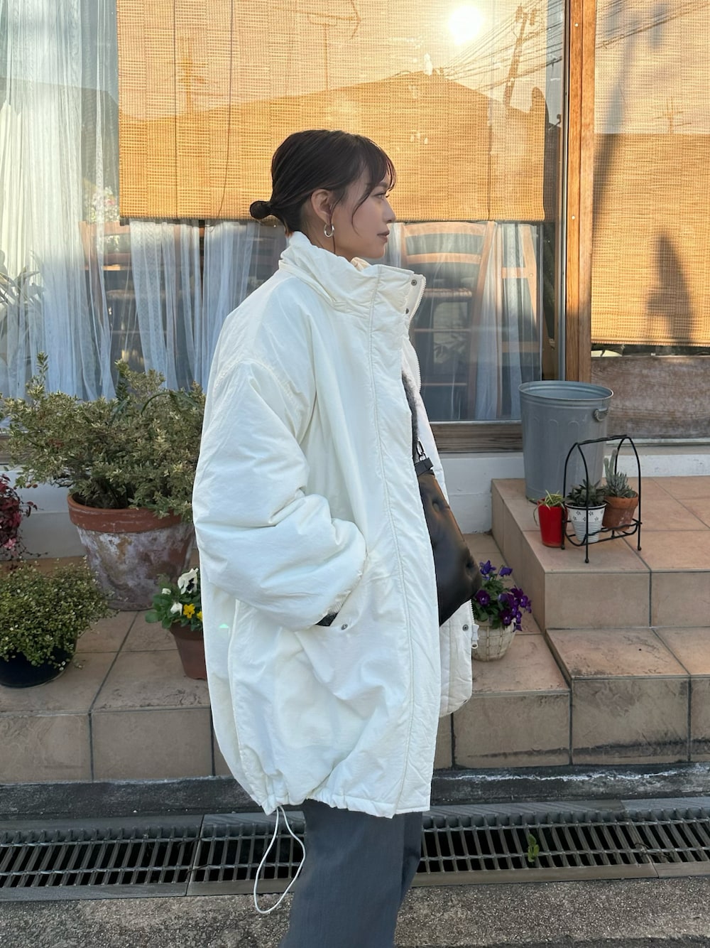 ホワイト系のダウンジャケット/コート、グレー系のスラックス、ブラック系のショルダーバッグを着用したレディースの冬コーディネートの1枚目の写真