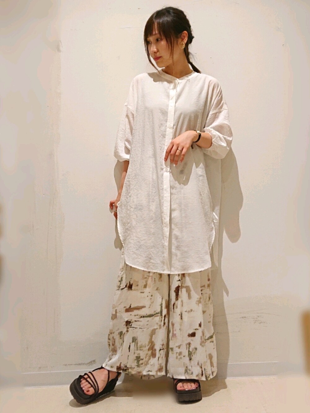 ベージュ系のその他パンツ、ホワイト系のチュニック、ブラウン系のサンダルを着用したレディースの夏コーディネートの1枚目の写真