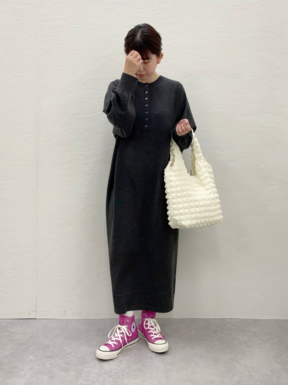 グレー系のワンピース、ホワイト系のトートバッグ、ピンク系のスニーカーを着用したレディースの冬コーディネートの1枚目の写真