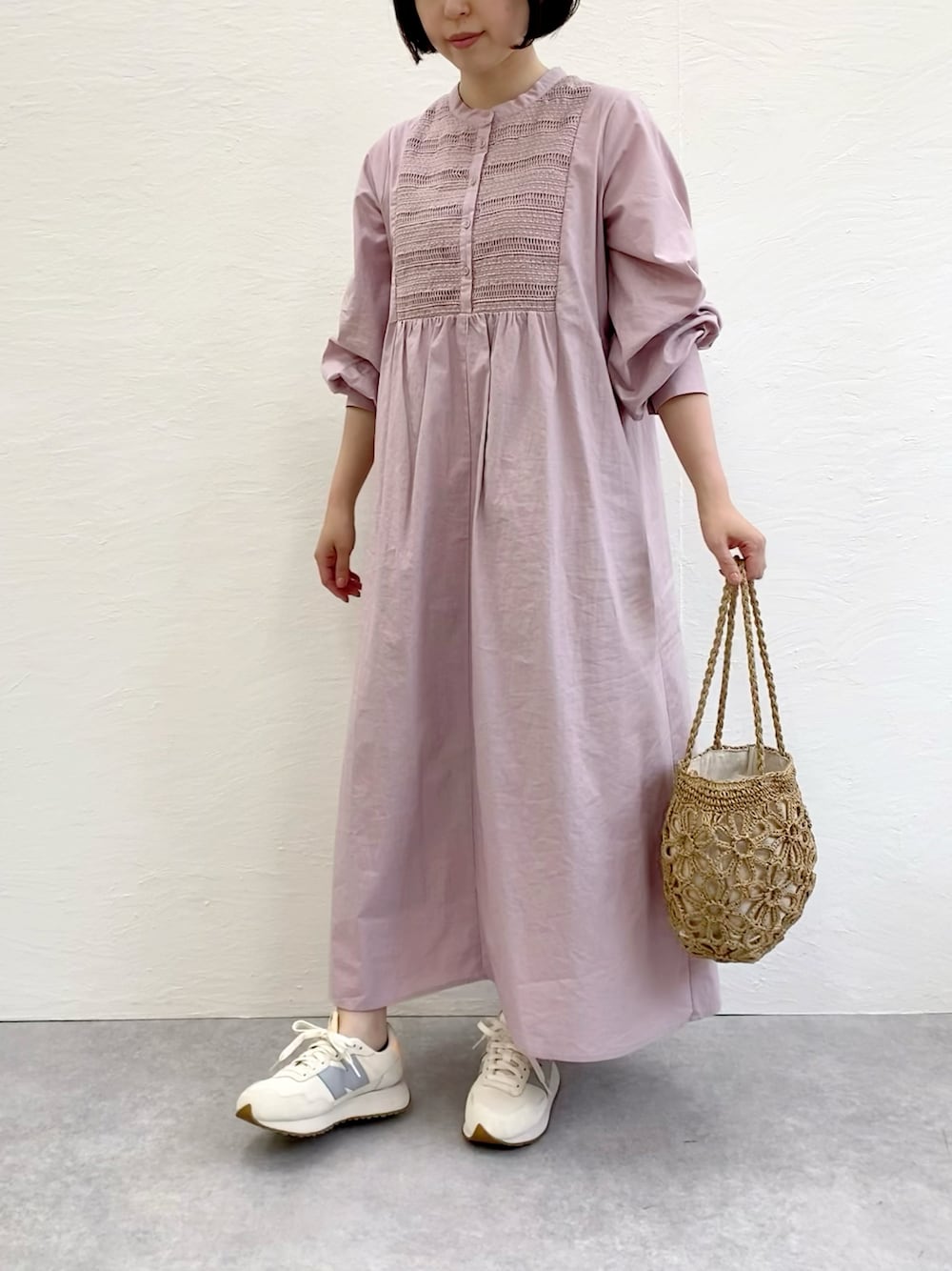 ベージュ系のかごバッグ、ホワイト系のスニーカー、ピンク系のシャツワンピースを着用したレディースの春コーディネートの1枚目の写真