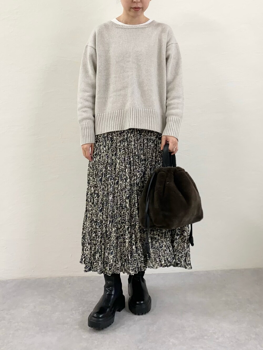 ブラック系のスカート、ブラック系のブーツ、グレー系のショルダーバッグを着用したレディースの秋コーディネートの1枚目の写真