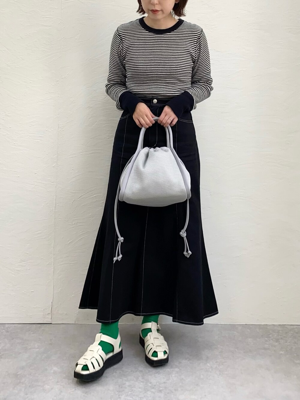 グレー系のショルダーバッグ、その他のTシャツ/カットソー、ブラック系のスカートを着用したレディースの春コーディネートの1枚目の写真