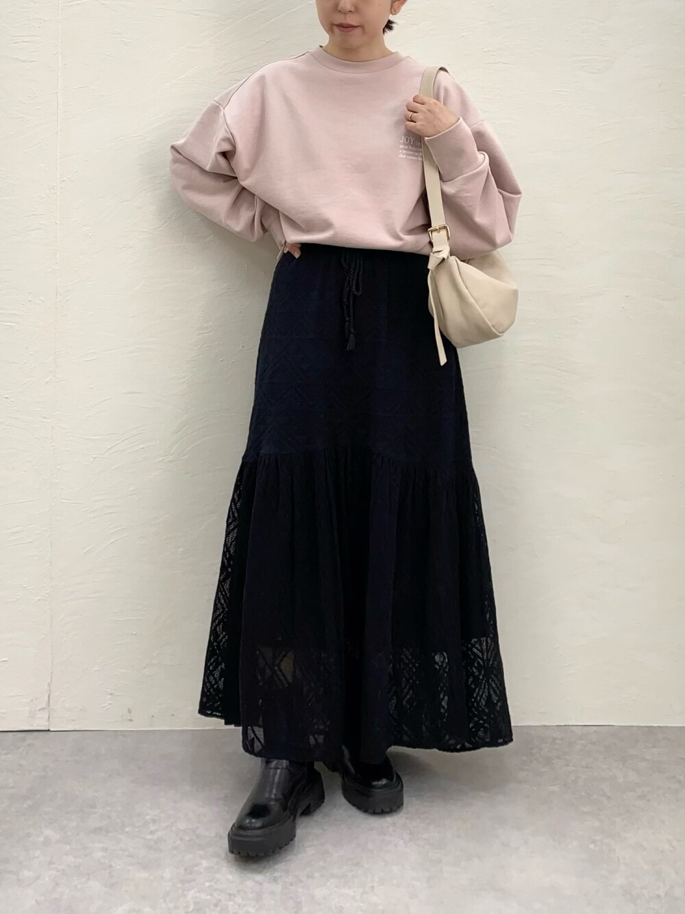 ピンク系のスウェット、ホワイト系のショルダーバッグ、ブラック系のブーツを着用したレディースの冬コーディネートの1枚目の写真