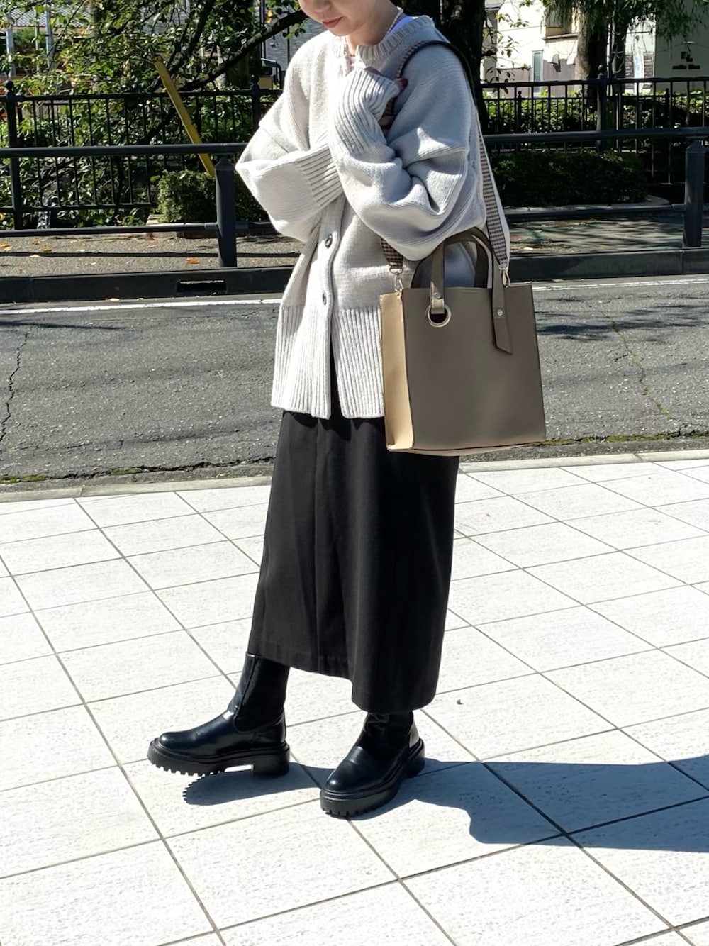 ベージュ系のトートバッグ、ブラック系のスカート、ブラック系のブーツを着用したレディースの秋コーディネートの1枚目の写真