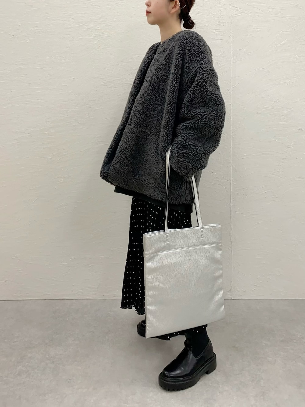 グレー系のブルゾン、シルバー系のトートバッグ、ブラック系のブーツを着用したレディースの冬コーディネートの1枚目の写真