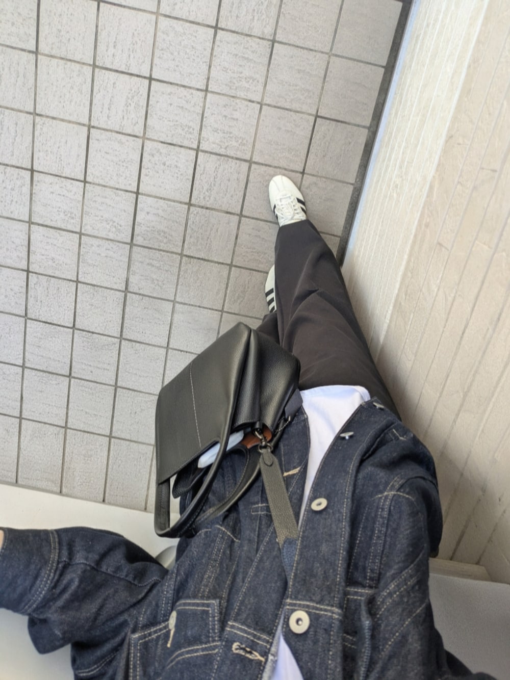 ホワイト系のスニーカー、ブラック系のスウェットパンツ、ブルー系のデニムジャケットを着用したレディースの春コーディネートの1枚目の写真