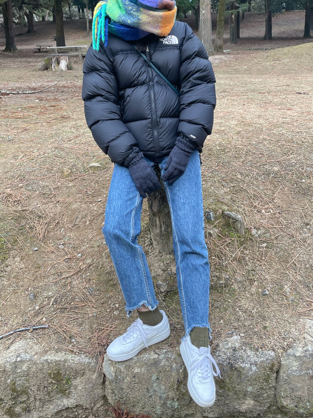 ホワイト系のスニーカー、ブルー系のデニムパンツ、ブラック系のダウンジャケット/コートを着用したレディースの冬コーディネートの1枚目の写真