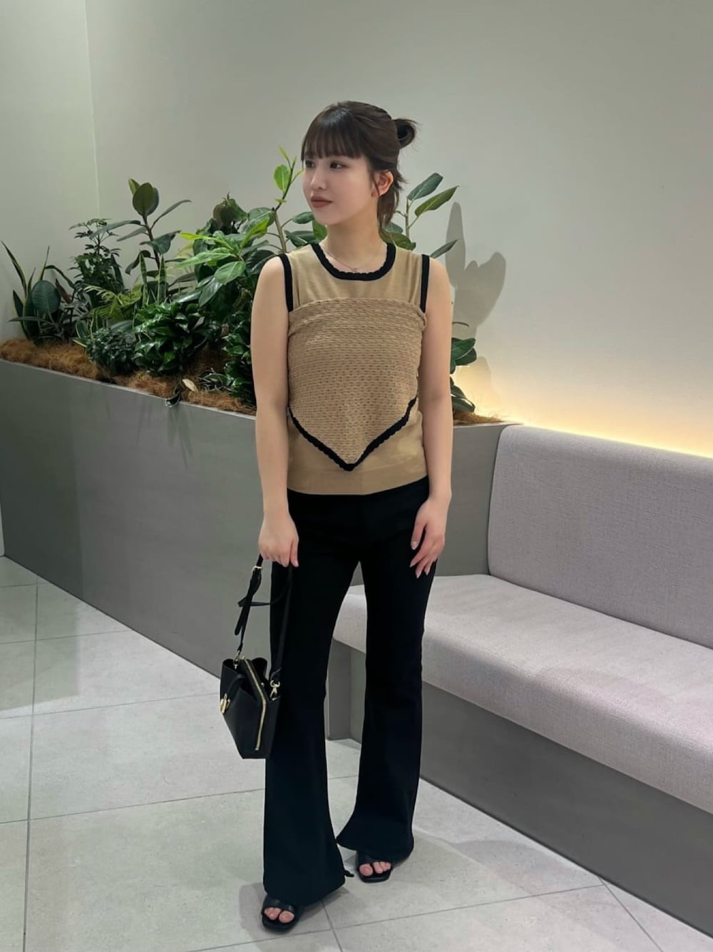 ベージュ系のニット/セーター、ブラック系のデニムパンツ、ブラック系のショルダーバッグを着用したレディースの夏コーディネートの1枚目の写真