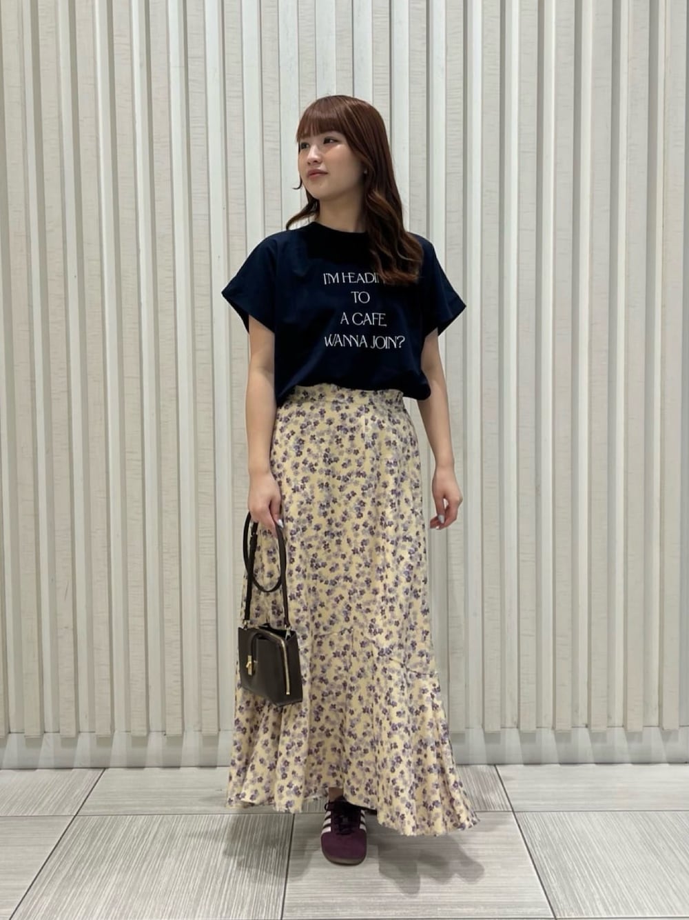 ブルー系のTシャツ/カットソー、イエロー系のスカート、ブラック系のショルダーバッグを着用したレディースの夏コーディネートの1枚目の写真