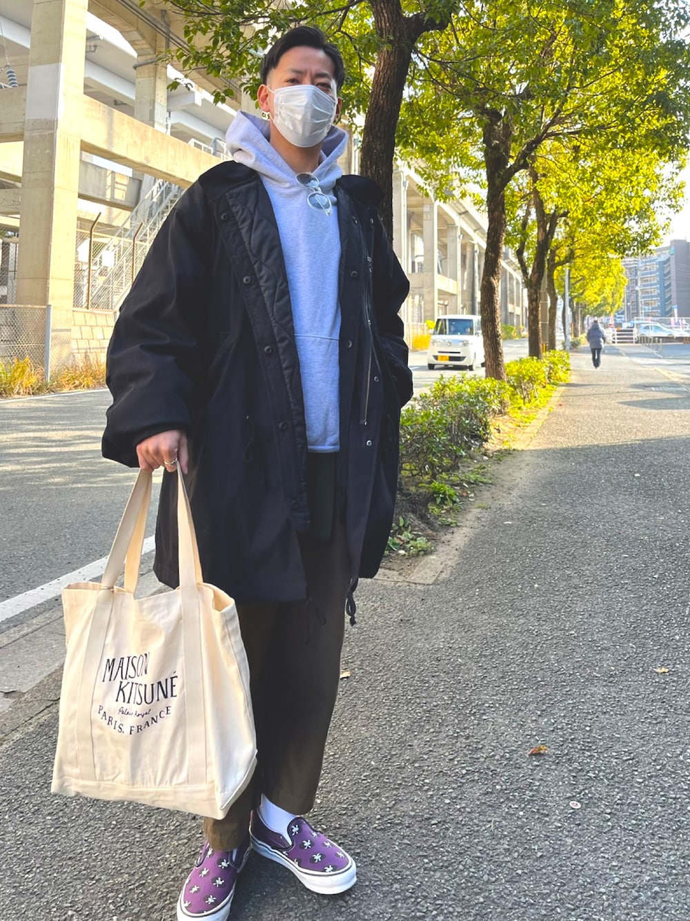 ベージュ系のトートバッグ、パープル系のスリッポン、グリーン系のチノパンツを着用したメンズの冬コーディネートの1枚目の写真