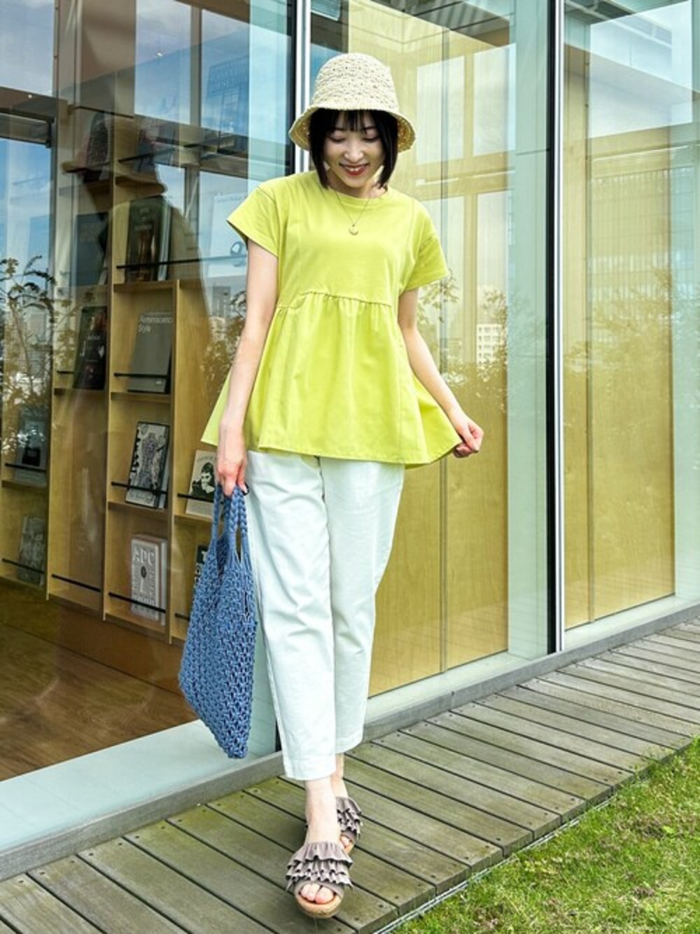 イエロー系のTシャツ/カットソー、ホワイト系のデニムパンツ、ブルー系のトートバッグを着用したレディースの春コーディネートの1枚目の写真
