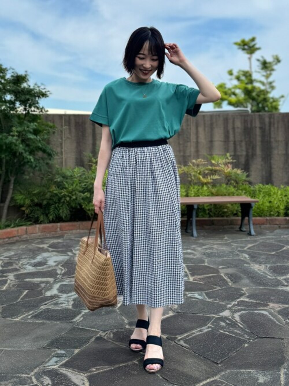 グリーン系のTシャツ/カットソー、ブラック系のスカート、ブラック系のサンダルを着用したレディースの夏コーディネートの1枚目の写真