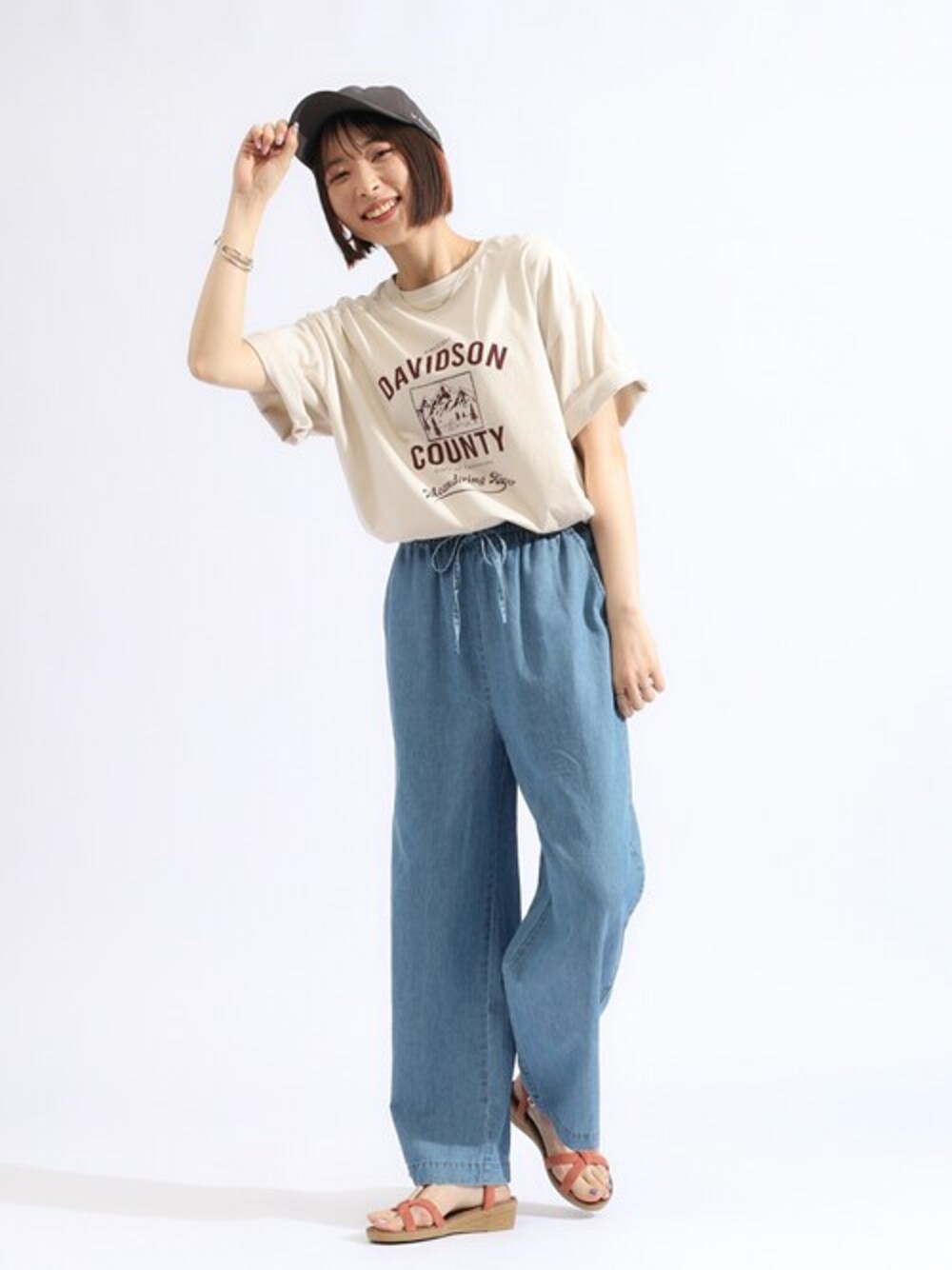 ベージュ系のTシャツ/カットソー、ブルー系のデニムパンツ、オレンジ系のサンダルを着用したレディースの夏コーディネートの1枚目の写真