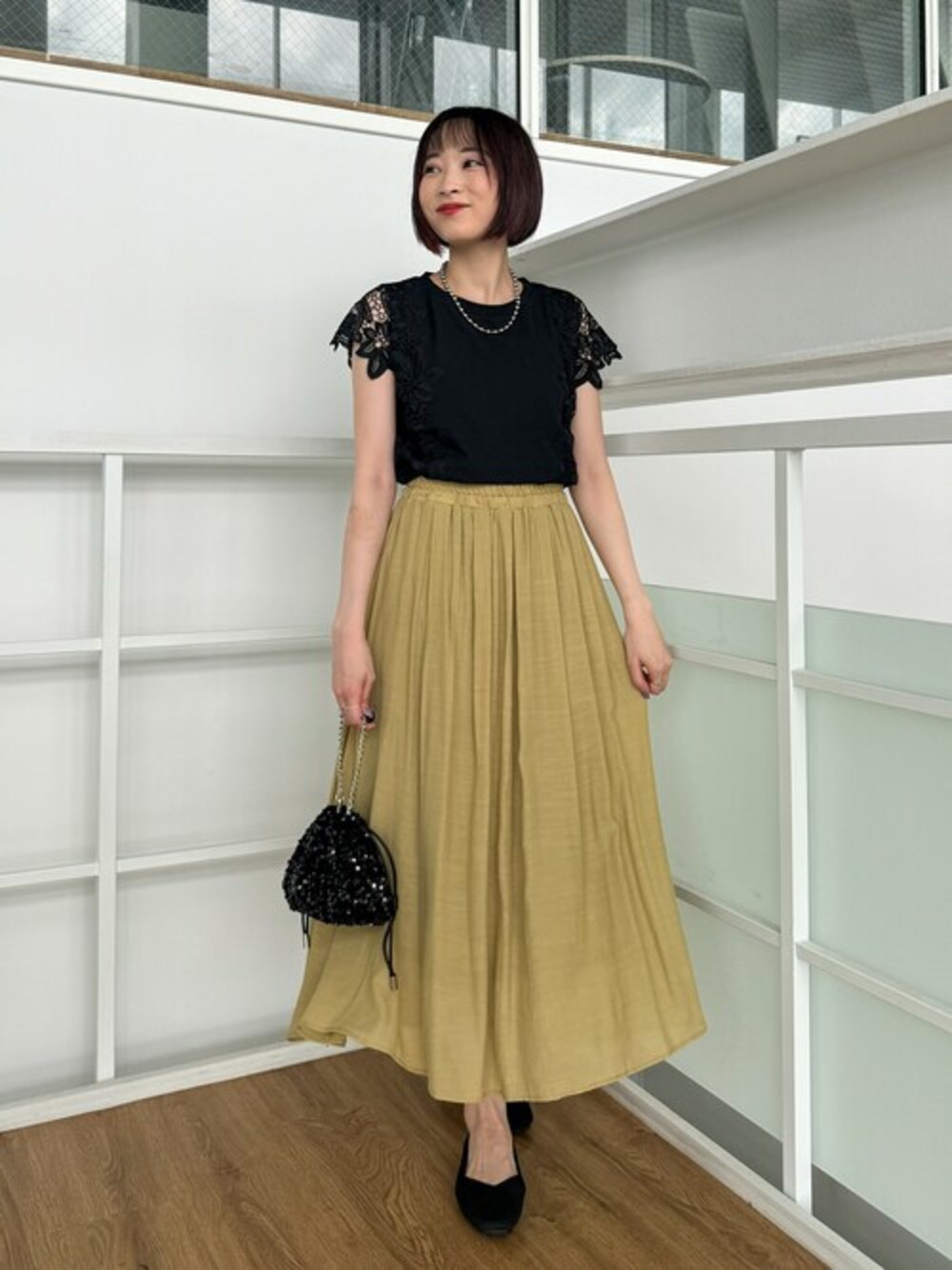 ブラック系のTシャツ/カットソー、イエロー系のスカート、シルバー系のパンプスを着用したレディースの夏コーディネートの1枚目の写真