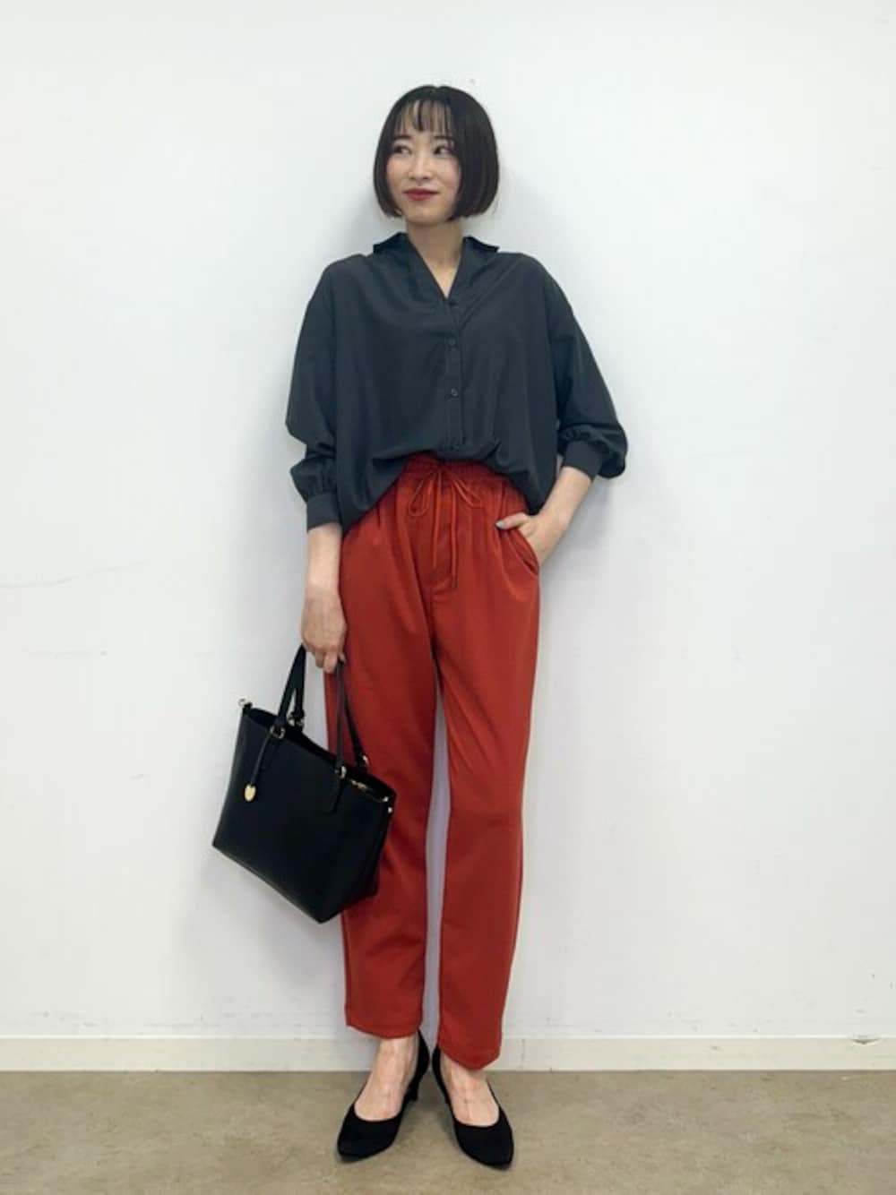 グレー系のシャツ/ブラウス、オレンジ系のその他パンツ、ブラック系のパンプスを着用したレディースの秋コーディネートの1枚目の写真