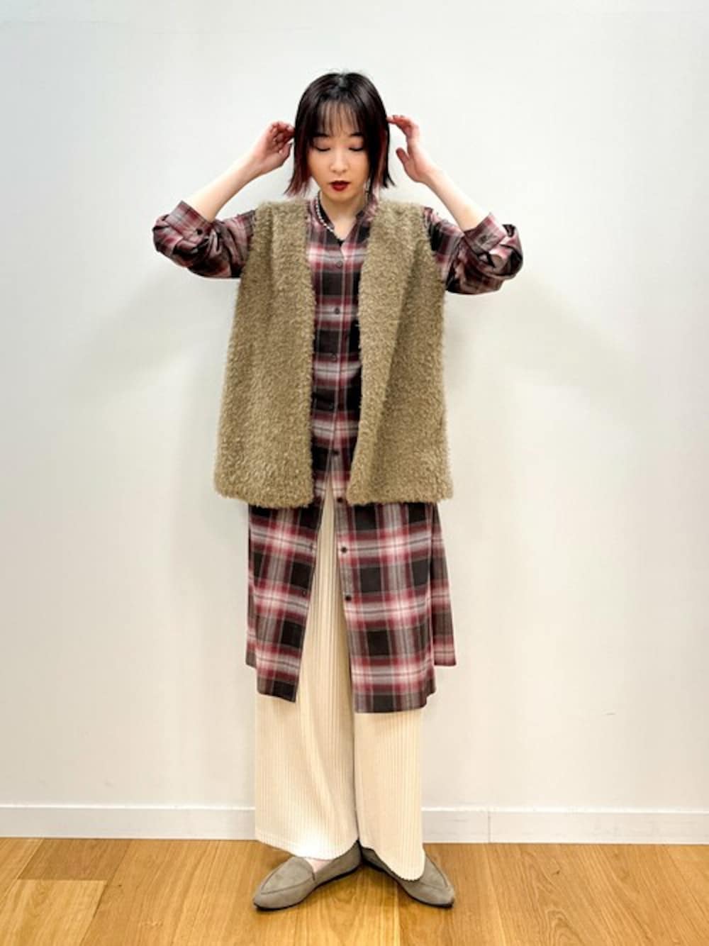 レッド系のワンピース、ブラウン系のベスト、ベージュ系のその他パンツを着用したレディースの秋コーディネートの1枚目の写真