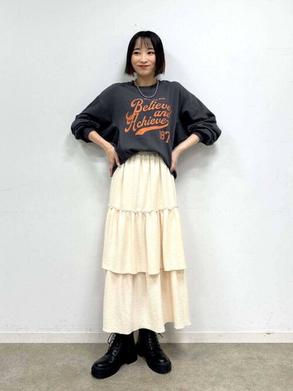 グレー系のスウェット、ホワイト系のスカート、ブラック系のブーツを着用したレディースの秋コーディネートの1枚目の写真