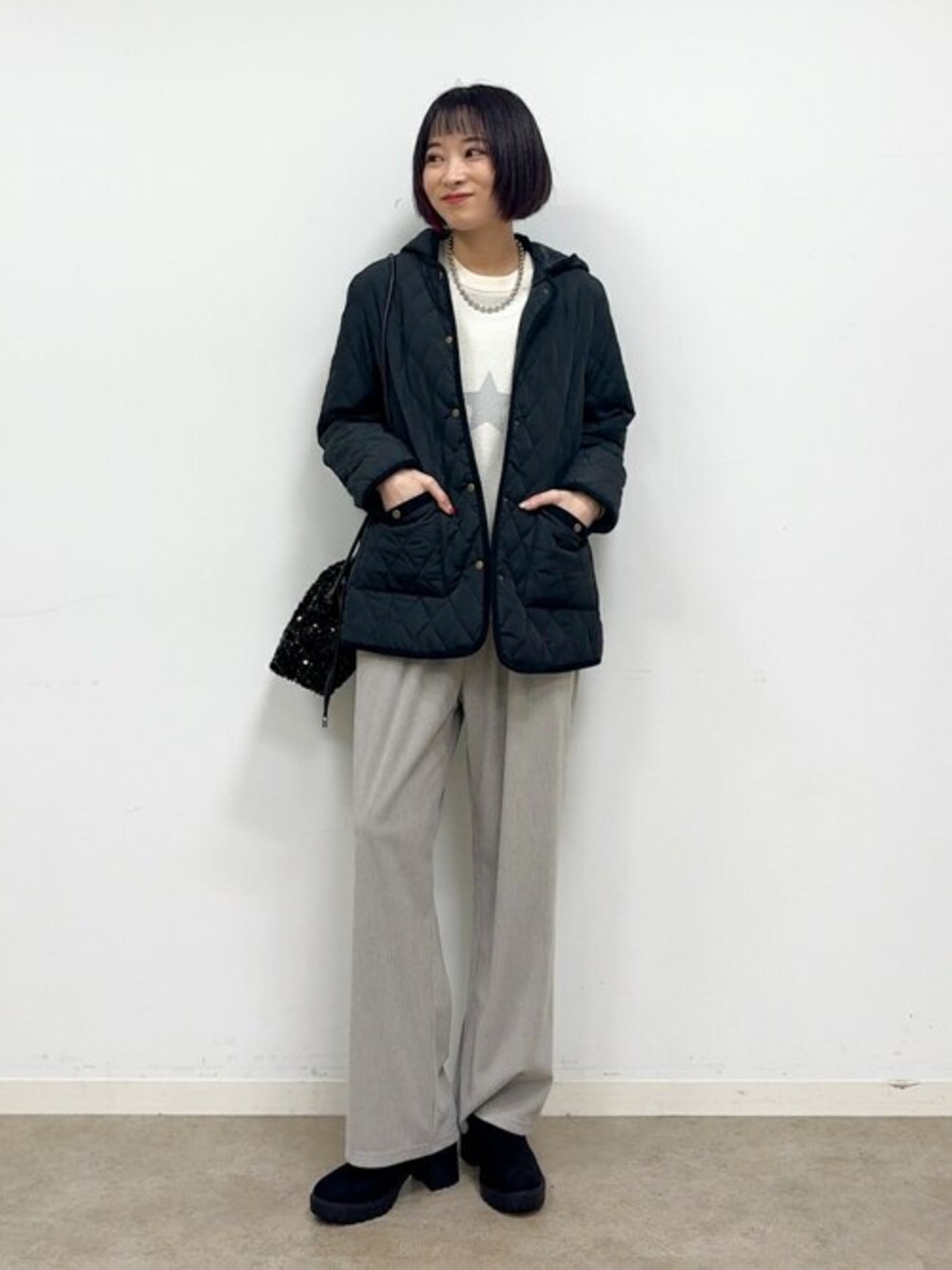 ブラック系のその他アウター、ホワイト系のニット/セーター、グレー系のその他パンツを着用したレディースの秋コーディネートの1枚目の写真