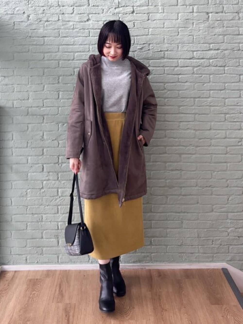 ブラウン系のその他アウター、グレー系のニット/セーター、イエロー系のスカートを着用したレディースの秋コーディネートの1枚目の写真
