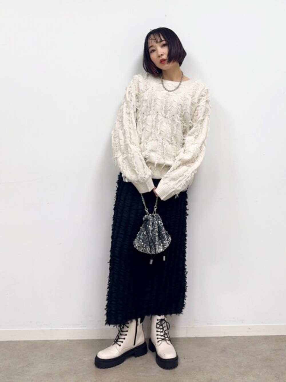 ブラック系のスカート、ホワイト系のブーツ、シルバー系のショルダーバッグを着用したレディースの冬コーディネートの1枚目の写真