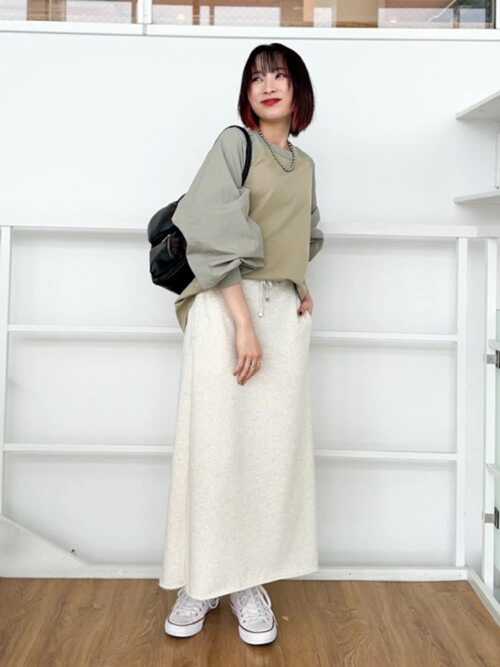 グリーン系のTシャツ/カットソー、グレー系のスカート、ブラック系のショルダーバッグを着用したレディースの春コーディネートの1枚目の写真