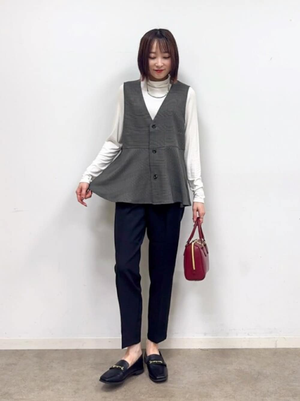グレー系のベスト、ホワイト系のTシャツ/カットソー、ブラック系のその他パンツを着用したレディースの秋コーディネートの1枚目の写真