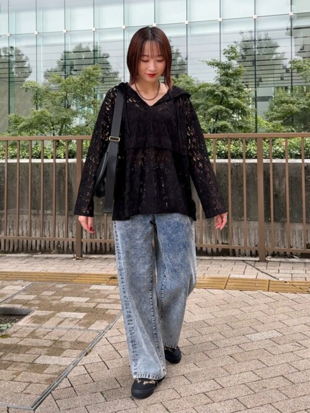 ブラック系のシャツ/ブラウス、ブルー系のデニムパンツ、ブラウン系のスニーカーを着用したレディースの秋コーディネートの1枚目の写真