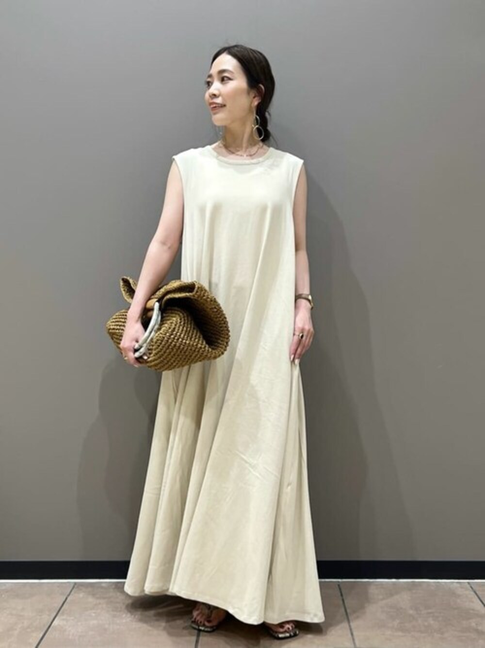 ベージュ系のかごバッグ、グレー系のサンダルを着用したレディースの夏コーディネートの1枚目の写真