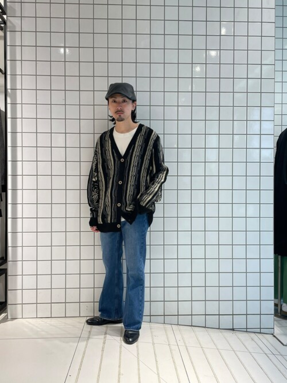 ブラック系のカーディガン/ボレロ、ブルー系のデニムパンツ、ブラック系のハンチング/ベレー帽を着用したメンズの秋コーディネートの1枚目の写真