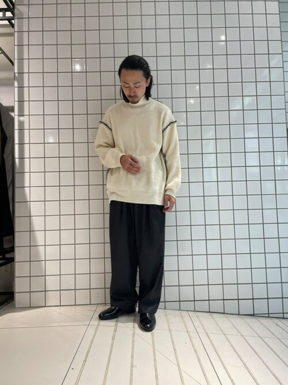 ホワイト系のニット/セーター、グレー系のスラックスを着用したメンズの冬コーディネートの1枚目の写真