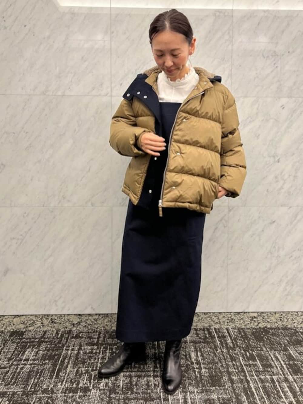 ベージュ系のダウンジャケット/コート、ブルー系のジャンパースカート、ホワイト系のシャツ/ブラウスを着用したレディースの秋コーディネートの1枚目の写真