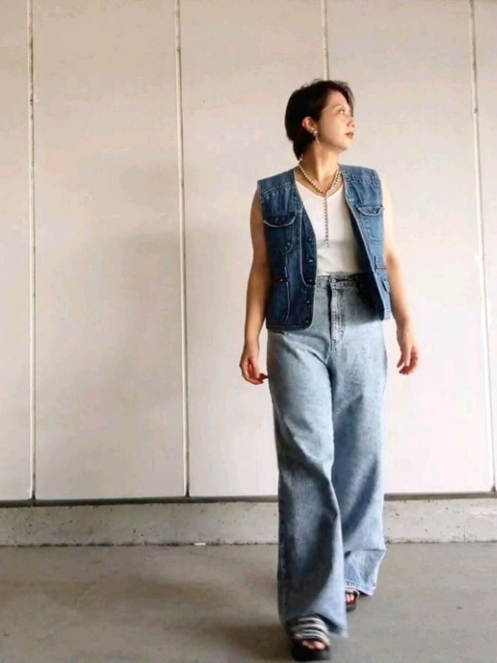 ブルー系のデニムパンツ、ホワイト系のタンクトップ、ブルー系のベストを着用したレディースの夏コーディネートの1枚目の写真