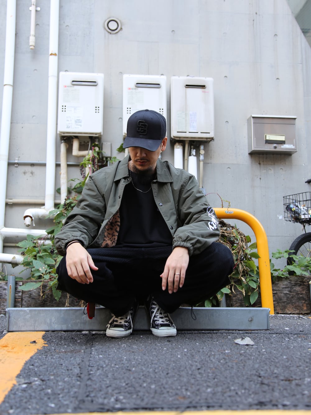 ブラック系のスラックス、グリーン系のブルゾン、ブラック系のキャップを着用したメンズの秋コーディネートの1枚目の写真