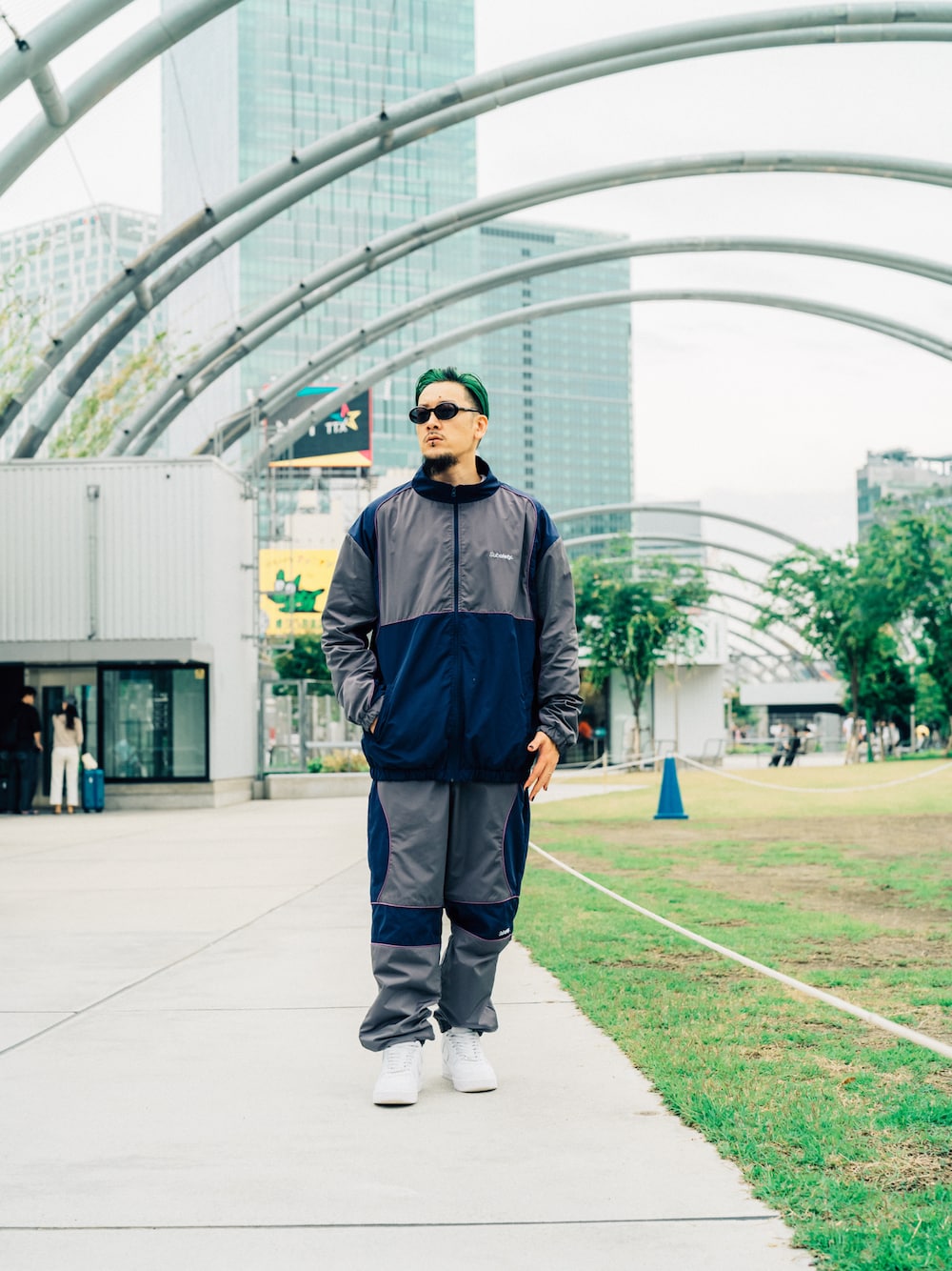 グレー系のその他パンツ、グレー系のナイロンジャケット、ブラック系のサングラスを着用したメンズの夏コーディネートの1枚目の写真